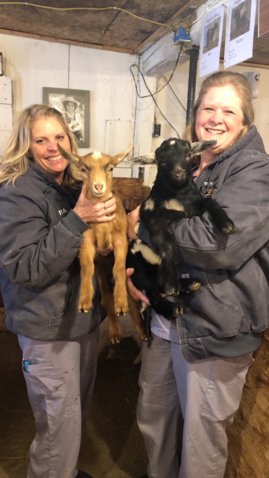 Patrice and Dr. Erin holding two baby goats on a farm visit